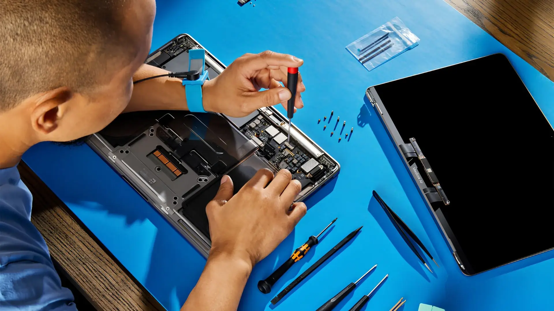 Professional technician performing tablet repair by replacing a broken screen using precision tools on a repair workstation